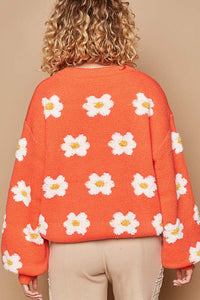 Woman wearing an orange drop shoulder sweater with daisy design, round neck, long sleeves, oversized fit, winter clothes, women's winter clothes