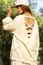 Load image into Gallery viewer, Woman wearing a cream sweatshirt with back cross strap detail and balloon sleeves, perfect winter clothes for women.
